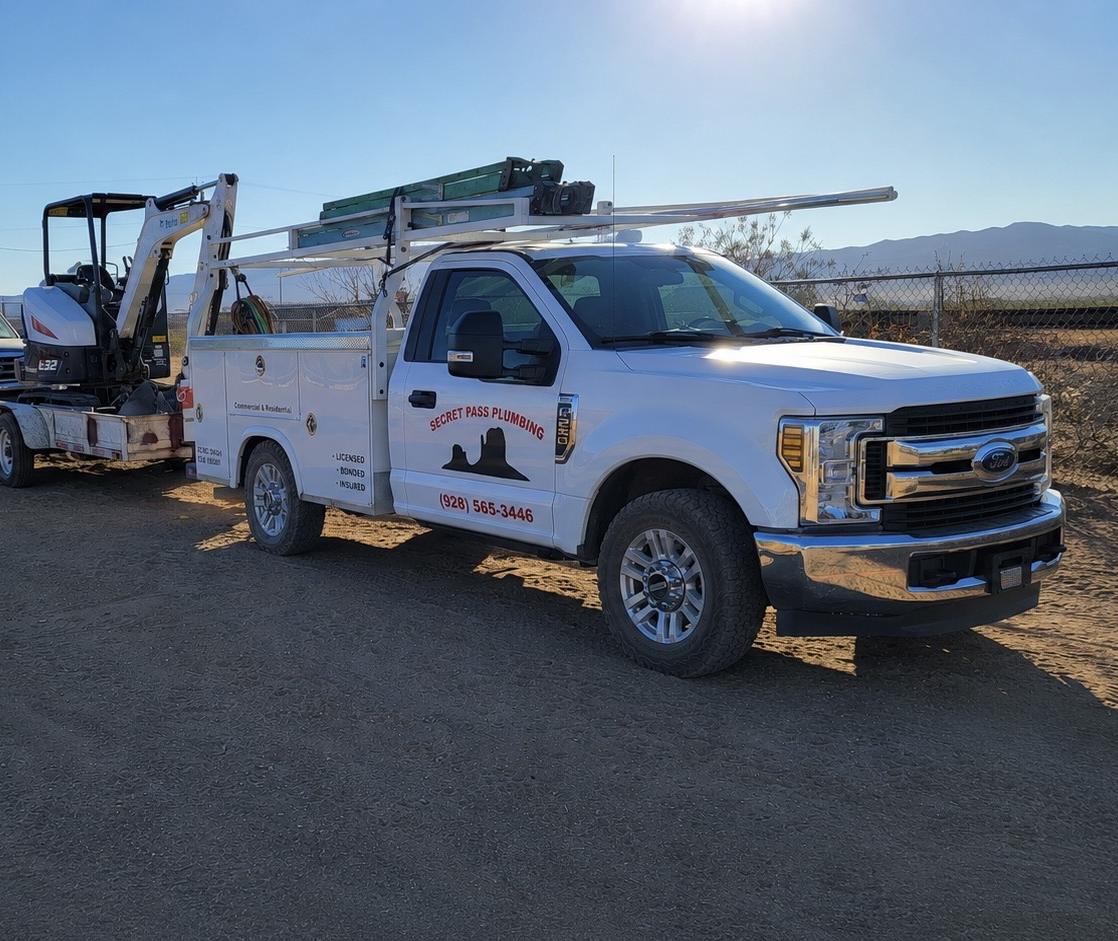 Secret Pass Plumbing service truck loaded with a mini excavator, ready for a job in Golden Valley